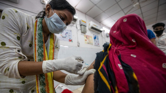 A healthcare worker with a mask giving a shot to a patient